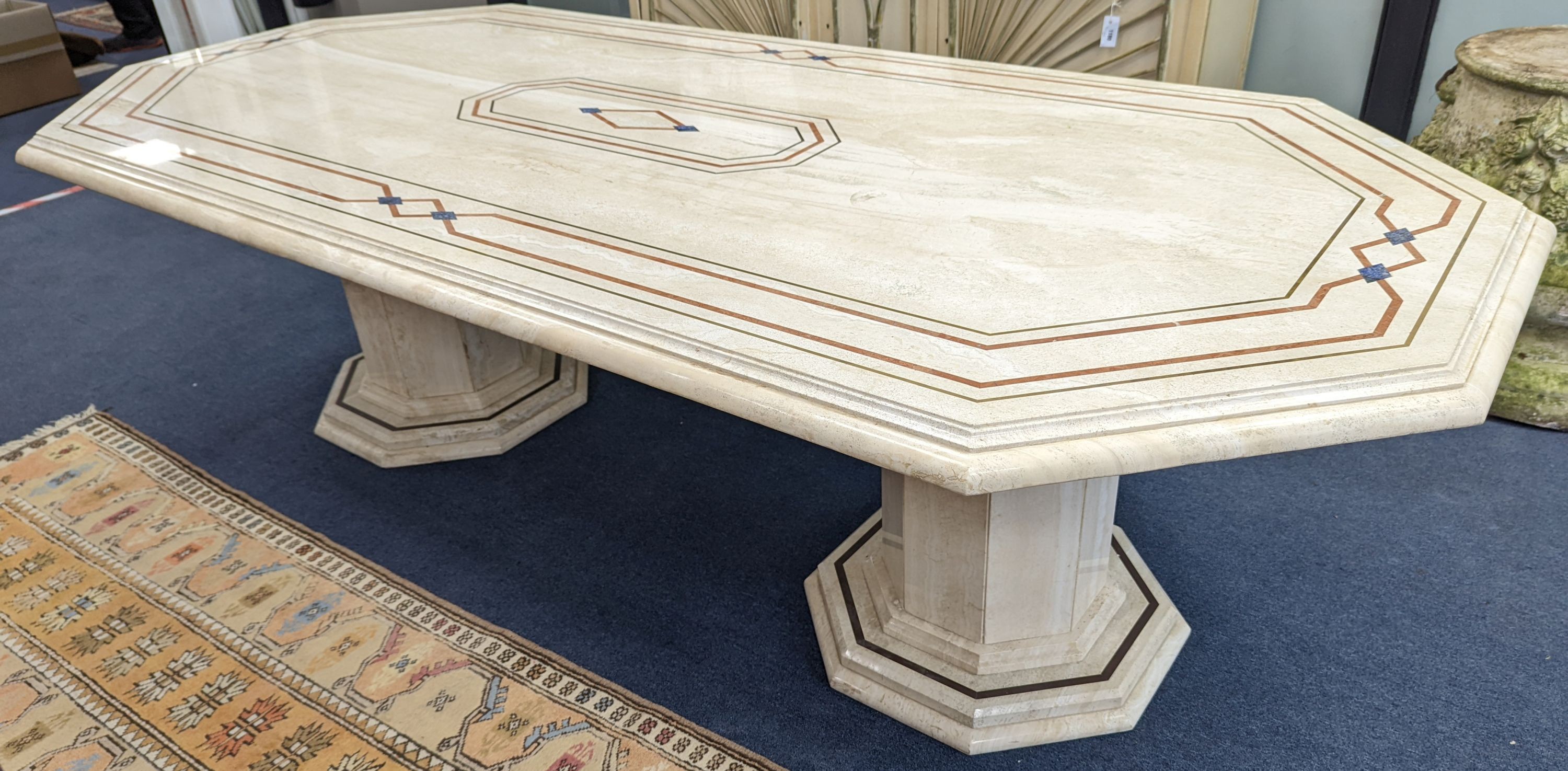 A Travertine marble dining table of elongated ocgtagonal form on twin octagonal column supports, length 260cm, depth 120cm, height 74cm